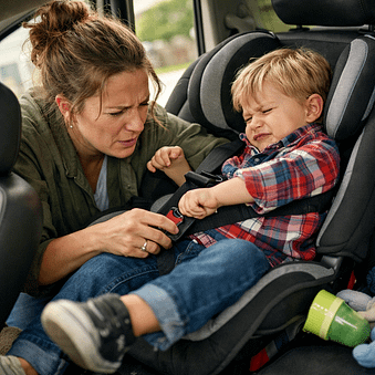 A relatable lifestyle shot of a parent struggling to buckle a child into a car seat